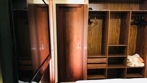 A bedroom with a bed, wooden wardrobe, and a closet with hanging space.