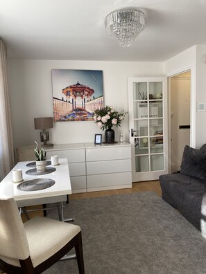 Relax in a stylish living space with a dining area, comfortable sofa, and decorative artwork.