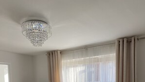 Una sala de estar moderna con una mesa de comedor, sillas, un televisor, lavadora y una araña.