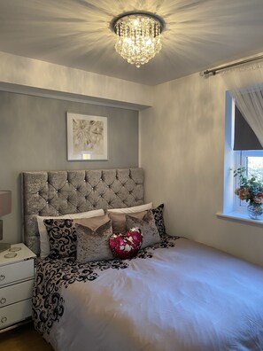 Cozy retreat with a tufted headboard, patterned bedding, and a statement artwork above the bed.