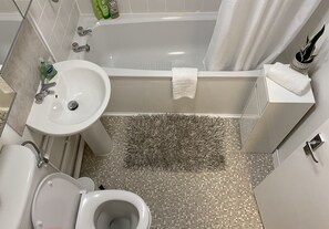 Bathroom features a bathtub, sink, and toilet, with toiletries and a towel holder.