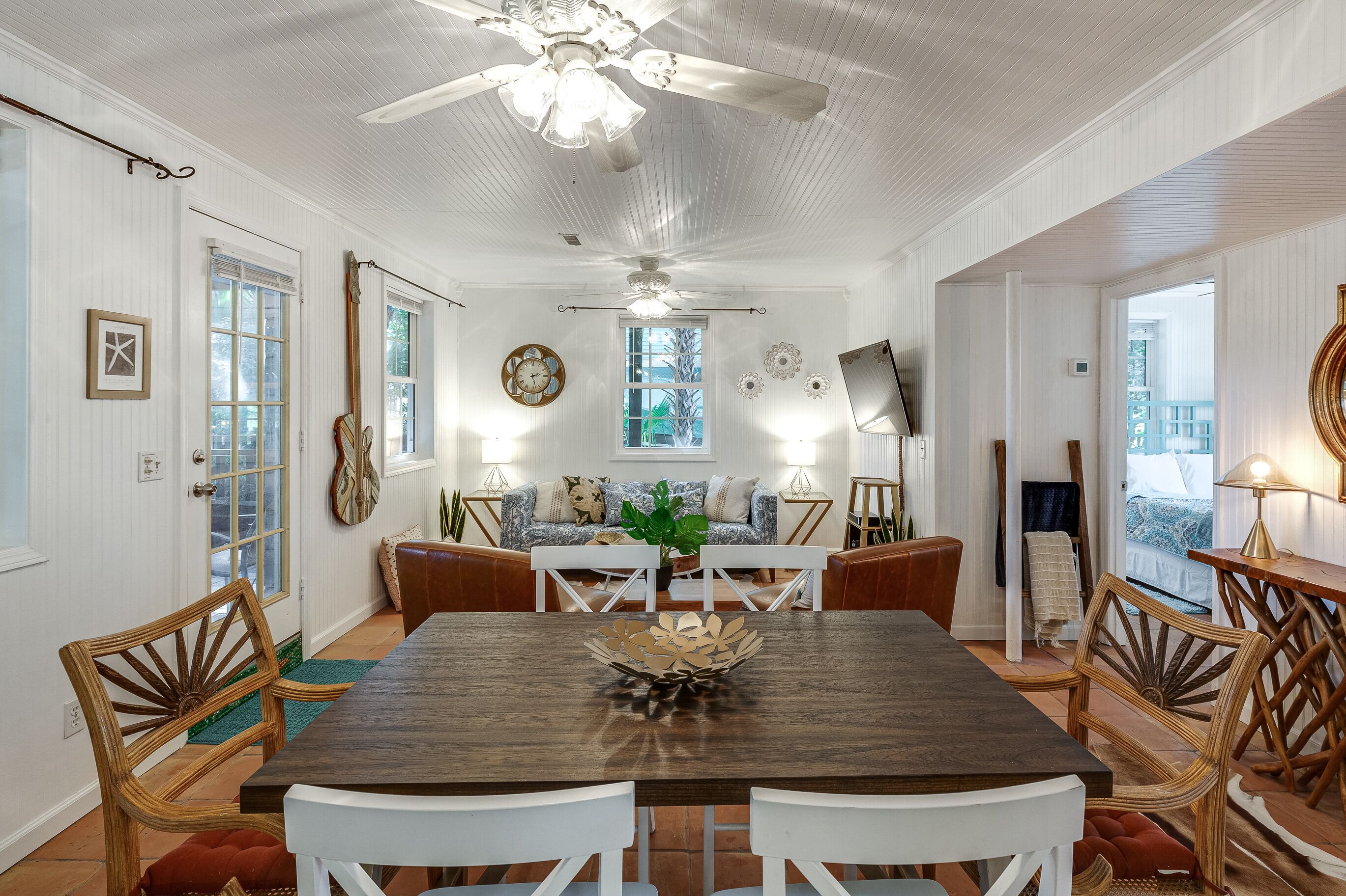 A dining area with a wooden table, white chairs, and a ceiling fan.
