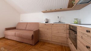 Eine kleine Küchenzeile mit einem Holzkorpus, einem eingebauten Ofen und einer Arbeitsplatte.