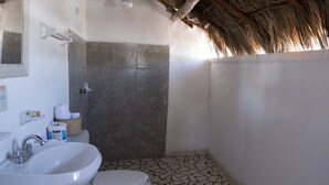 Ein Badezimmer mit weißem Waschbecken, Toilette und Duschbereich mit gefliestem Boden.