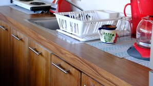 Eine Küche mit Holzausstattung, einem Mixer, einem Wasserkocher und einer roten Tasse auf der Arbeitsfläche.