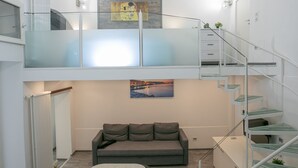 Ein modernes Interieur mit Glastrennwand, einer Couch, einem Gemälde und einer Treppe.