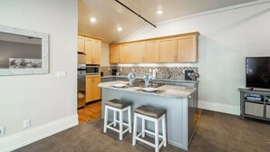 Una cocina moderna con armarios de madera, encimera de granito y una isla integrada con taburetes.