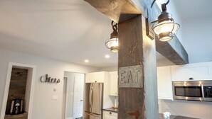 Una cocina moderna con un pilar de acento de madera, electrodomésticos de acero inoxidable y un letrero que dice 'EAT'.
