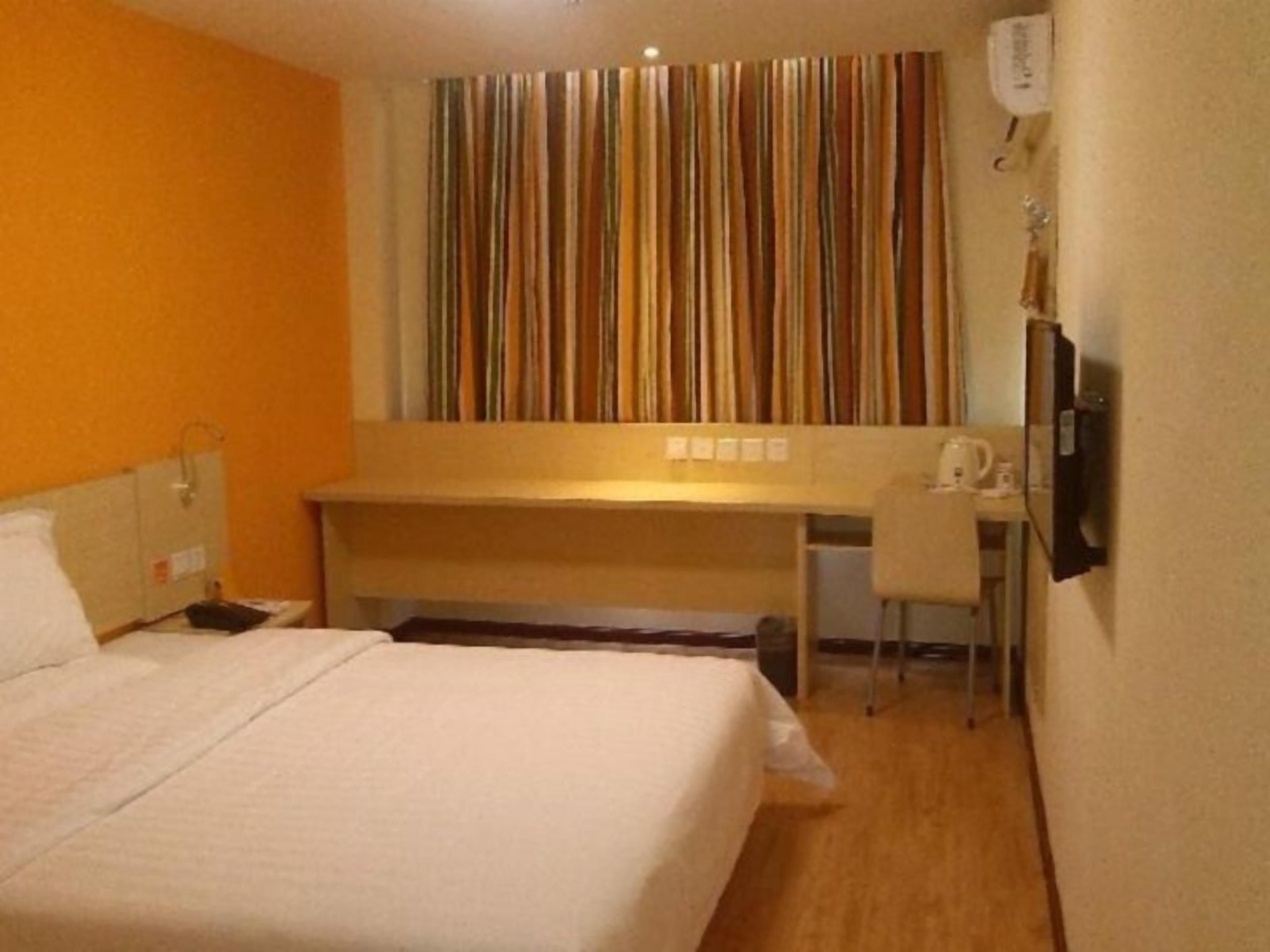 Una habitación de hotel con una cama, un escritorio, una silla y un televisor.