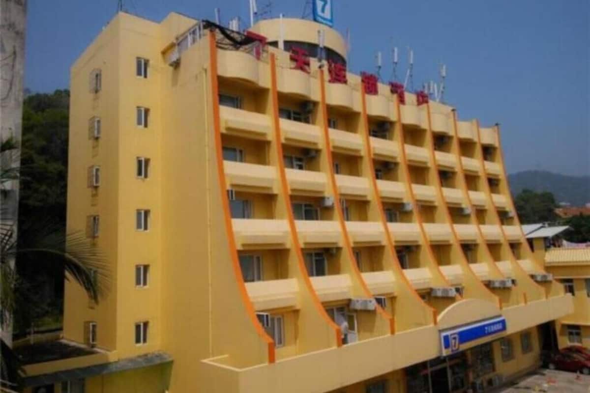 Ein mehrstöckiges Hotel mit gelber Fassade, Balkonen und einem blauen Schild mit dem Hotelnamen.