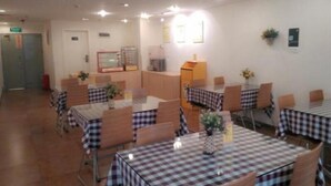 Un espace repas avec des nappes à carreaux, plusieurs tables, des chaises et des luminaires au plafond.