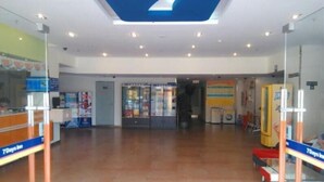 Un hall d’entrée spacieux avec un comptoir de réception, une cloison en verre et un grand logo bleu au plafond.