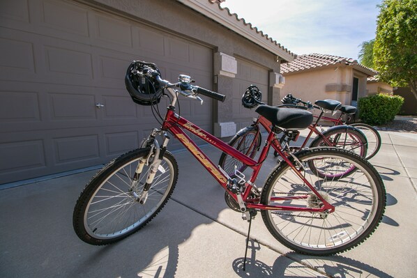 A red bicycle parked in front of a house with a garage.