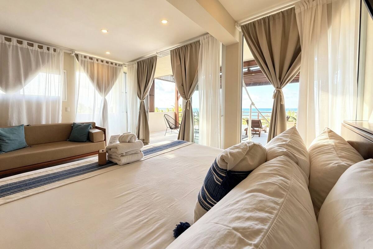 Ein Hotelzimmer mit Bett, einer Couch, einem Sessel und Blick auf das Meer.