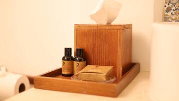A wooden tissue box with two bottles of lotion and a bar of soap on a tray.