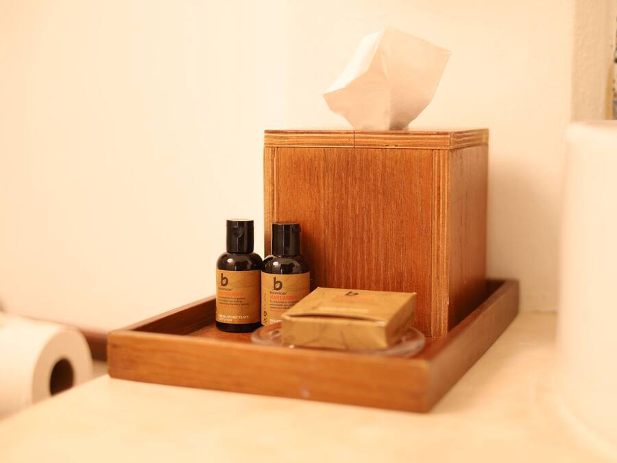 A wooden tissue box with two bottles of lotion and a bar of soap on a tray.