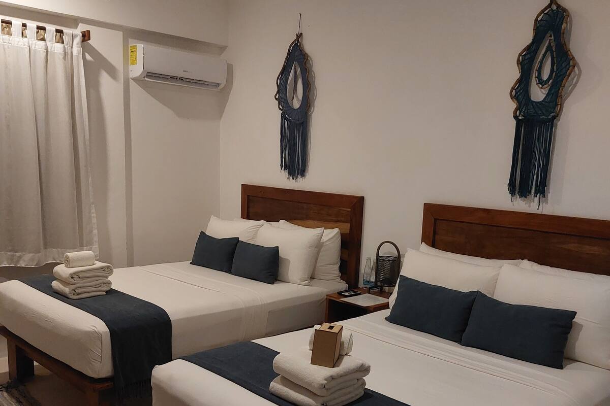 Ein Hotelzimmer mit zwei Betten, einem Deckenventilator, einer Klimaanlage und Wanddekorationen.