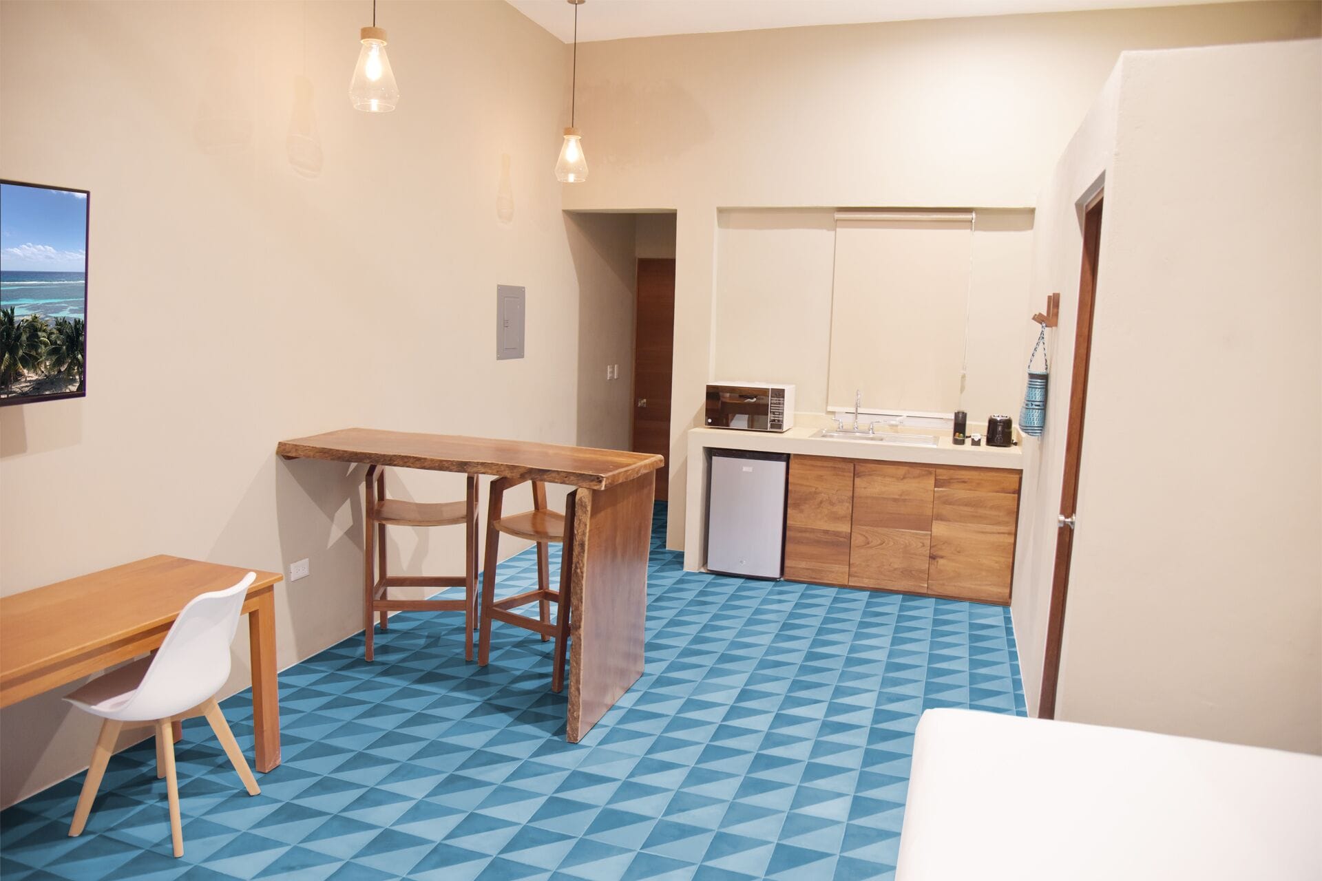 A compact kitchen with a wooden table and chairs, a microwave, and a sink.