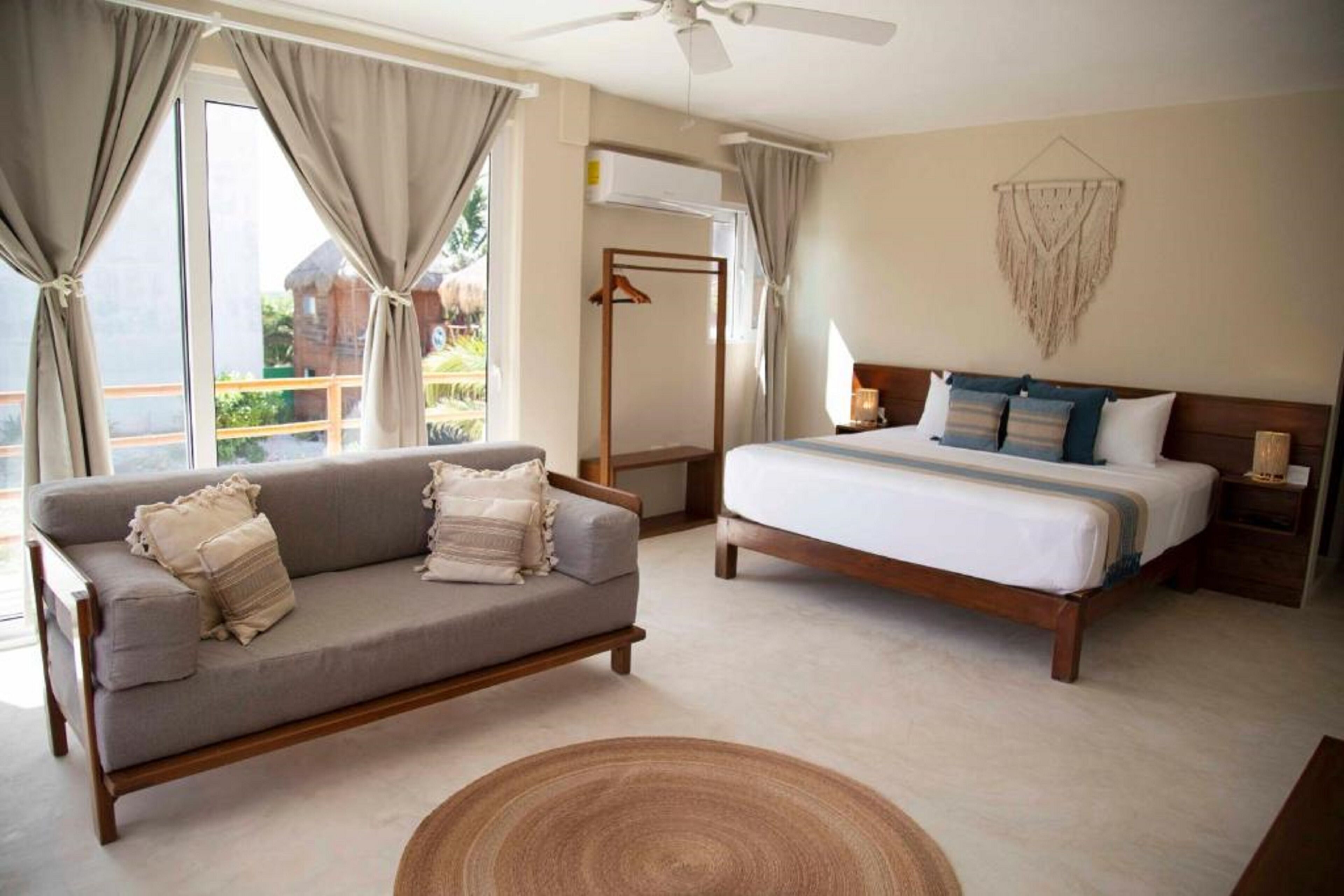 A bedroom with a bed, a sofa, and a ceiling fan.