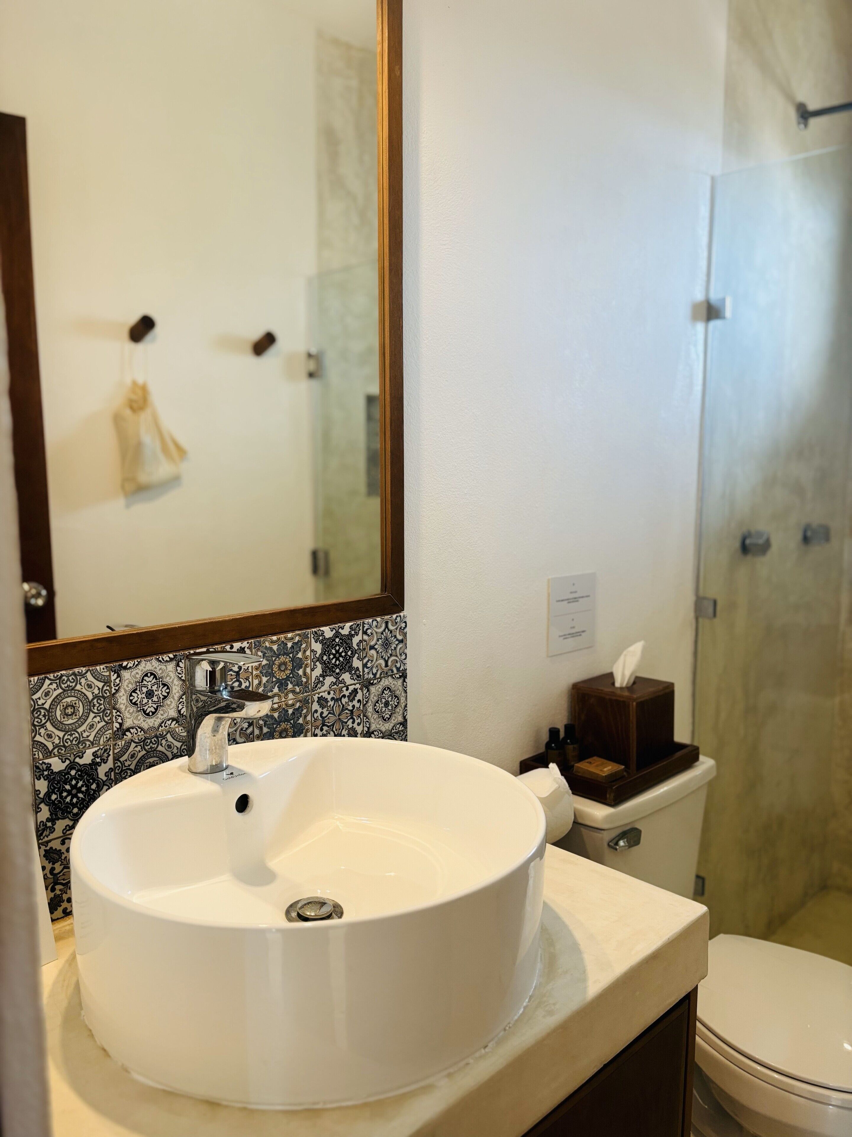 Un baño con un lavamanos blanco, un espejo y un inodoro.