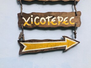 Un panneau en bois portant l’inscription « Xicotepec » et une flèche indiquant la direction à suivre, pointant vers la droite.