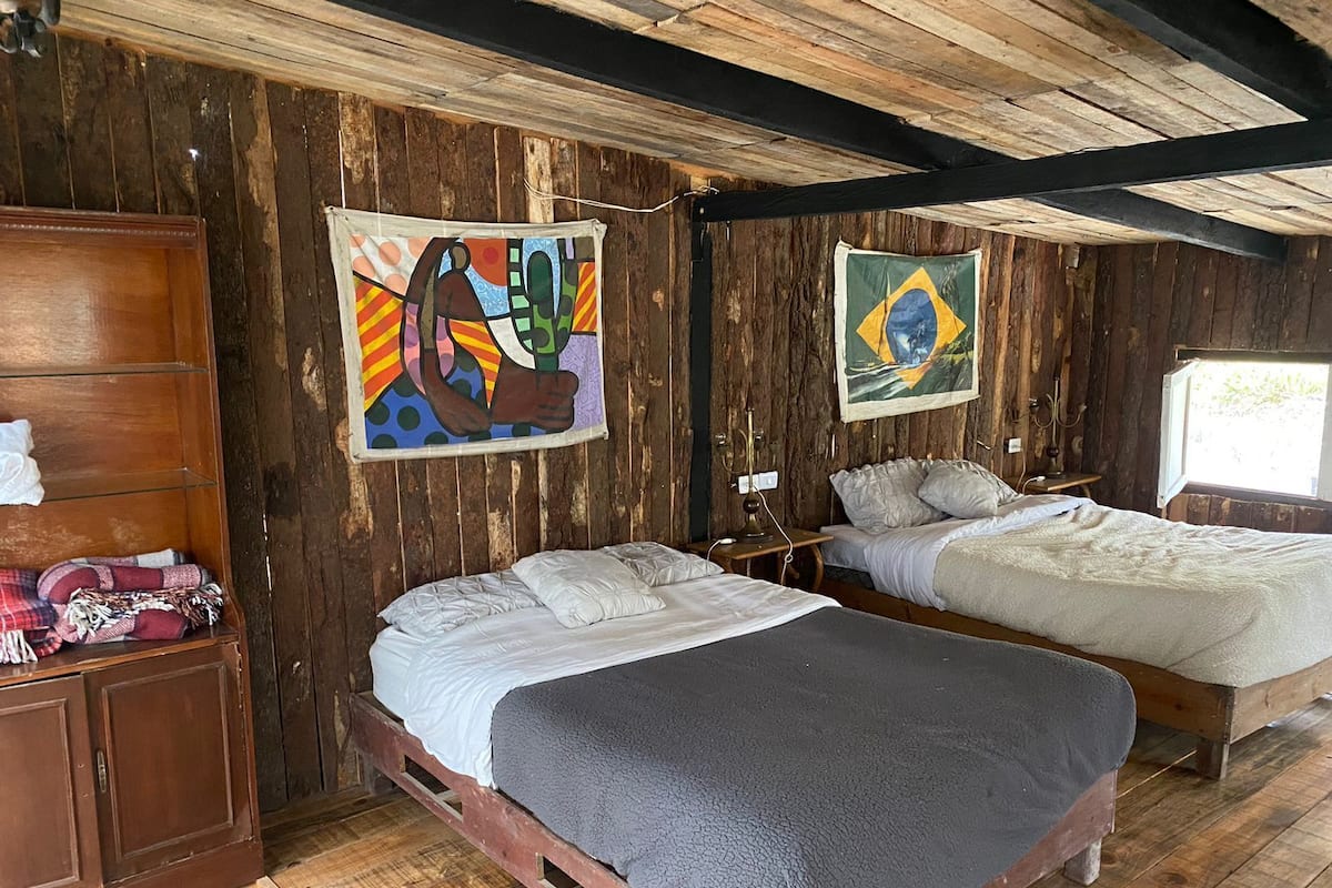 A rustic room with two beds, wooden walls, and a wooden ceiling.
