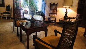 Une pièce chaleureuse avec une table en bois, des chaises, une lampe et une vue sur un jardin extérieur.