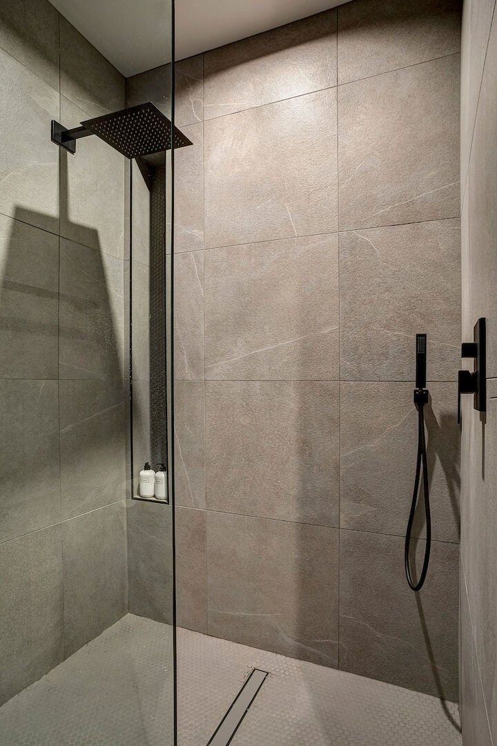 A modern shower area with a square showerhead and a handheld shower attachment.