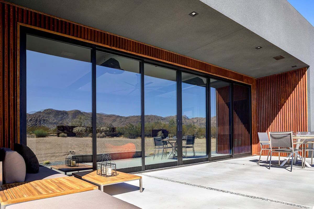 A modern interior with large glass windows, a wooden table, and a seating area.