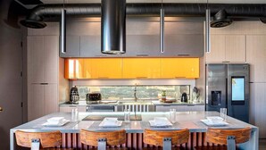 Una cocina moderna con una isla central, electrodomésticos de acero inoxidable y sillas de madera.