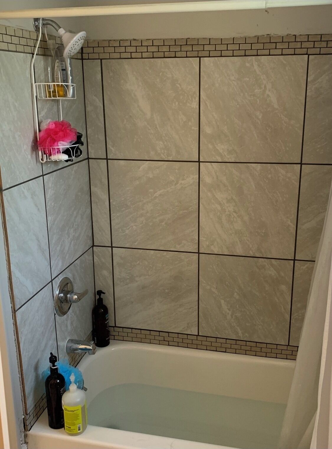 Une salle de bain équipée d’une baignoire, d’une douche, d’un porte-serviettes et d’articles de toilette.
