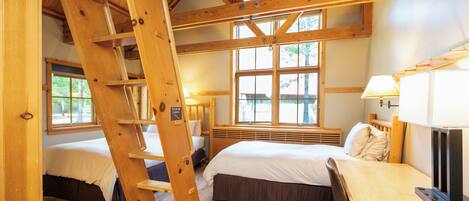 A wooden cabin with a loft bed, a desk, and a ladder.