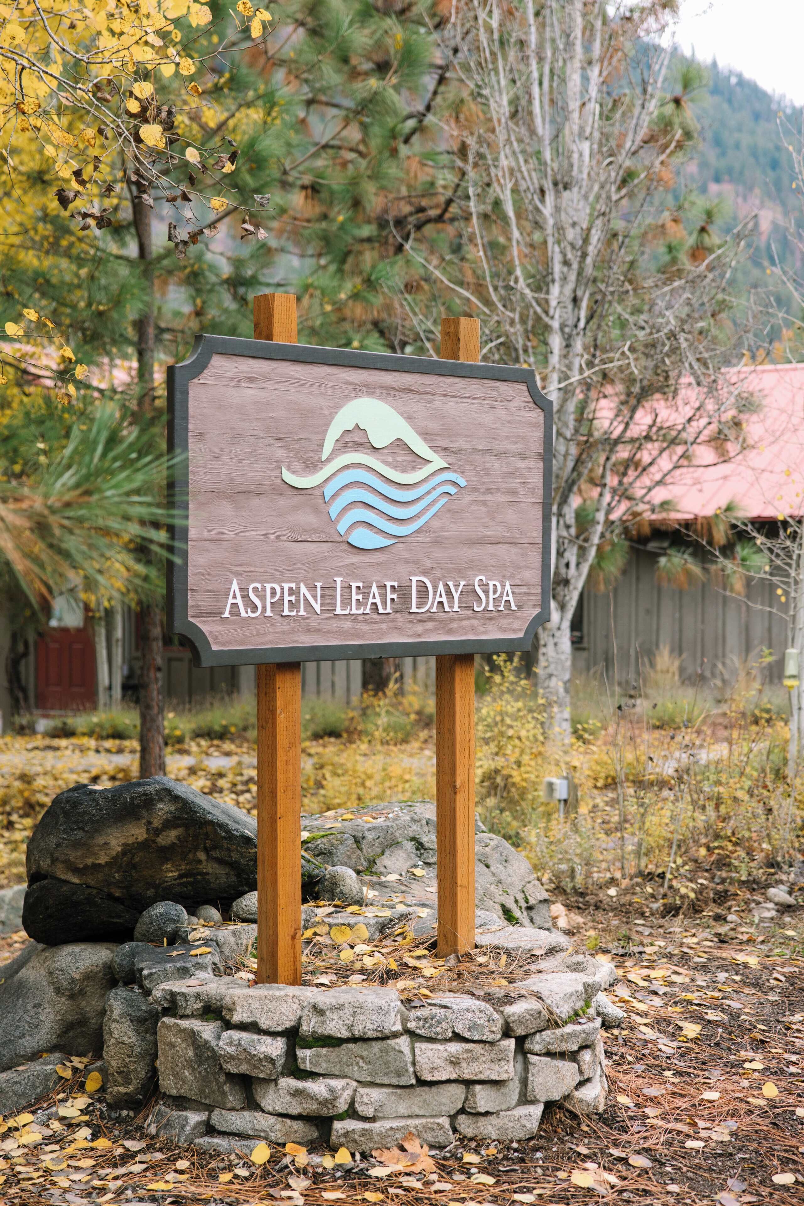 Un letrero de madera con el texto 'Aspen Leaf Day Spa' y un logotipo con forma de ola.