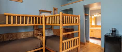 A bunk bed room with a kitchenette and a window.