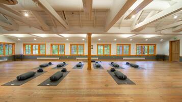 Amplia habitación con pisos de madera, ventanas grandes y esterillas de yoga dispuestas para practicar.