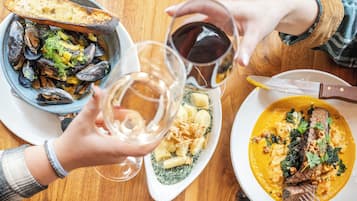 Una mesa de comedor con platos de comida, una copa de vino y un cuchillo.