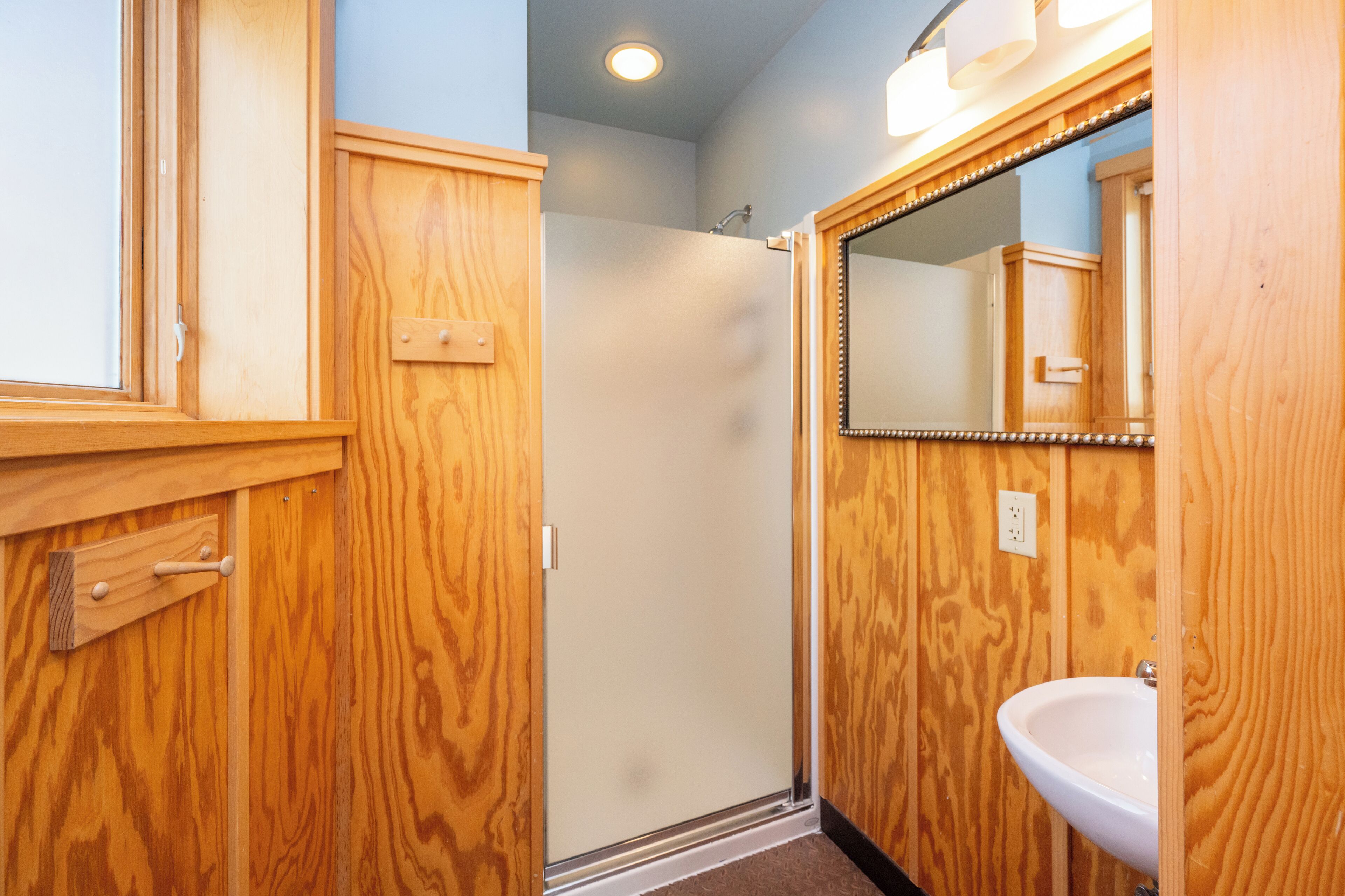 A wooden bathroom with a sink and mirror.