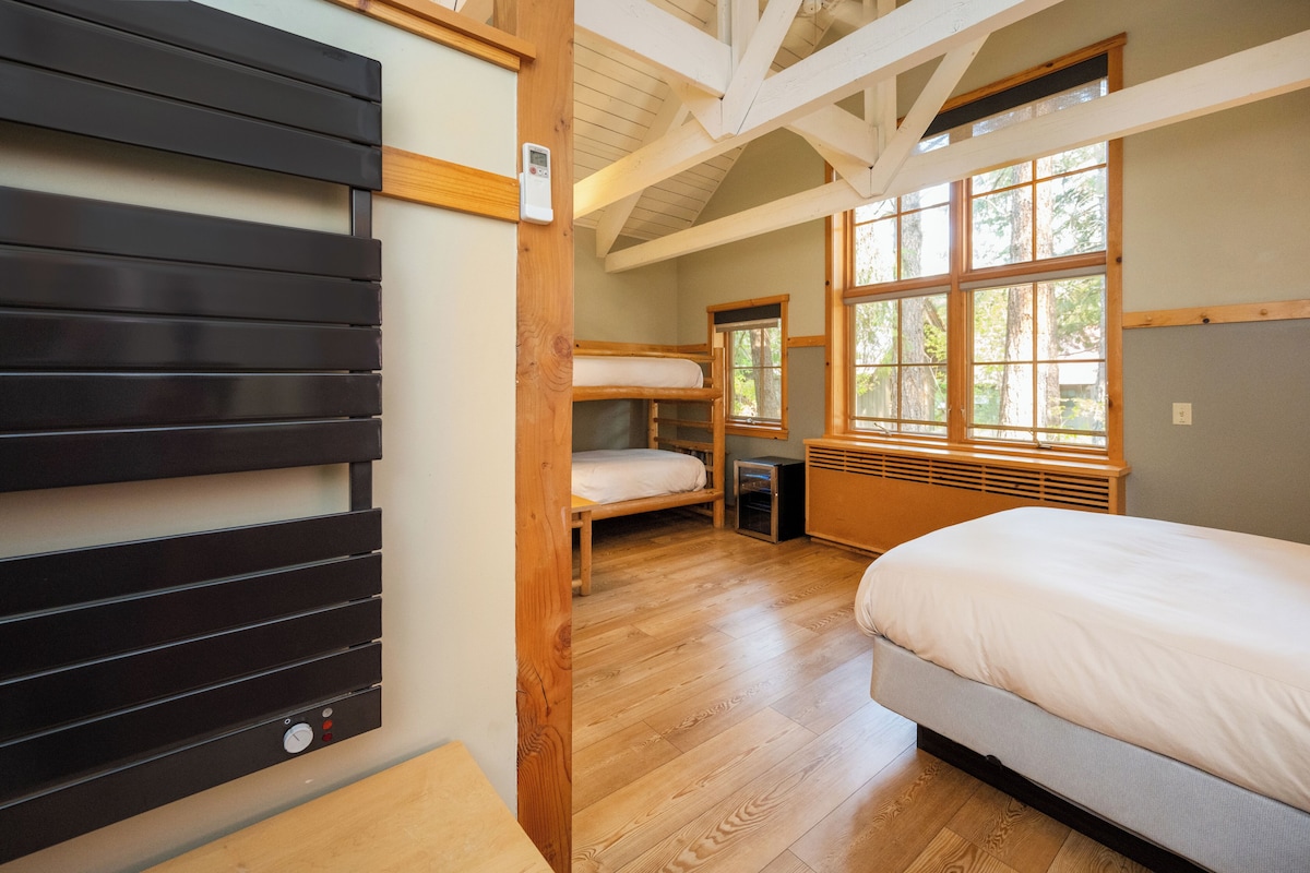 Ein Zimmer mit einem Etagenbett, einem Einzelbett und einer Holzbalkendecke.