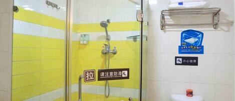 Un baño con cabina de ducha de vidrio, un perchero, un inodoro y un estante con artículos de aseo.