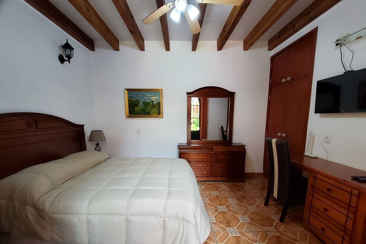Un dormitorio con cama, cómoda, tocador y televisor.