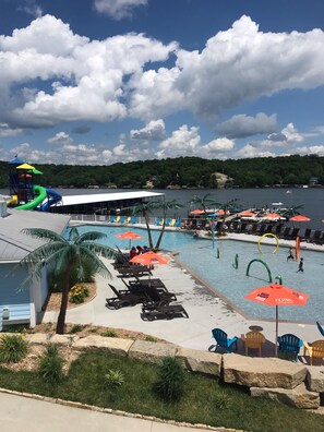 A pool area with lounge chairs, umbrellas, and a water slide.