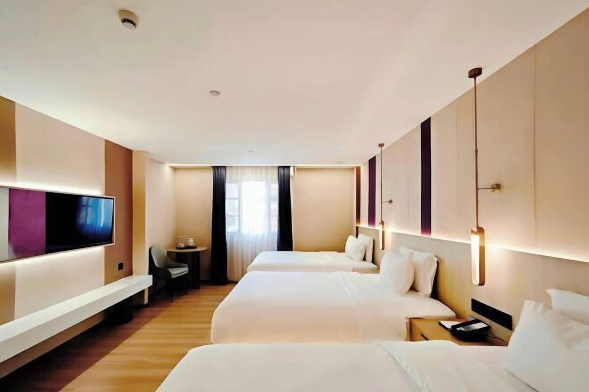 Ein Hotelzimmer mit zwei Betten, einem Fernseher, einem Schreibtisch und einem Stuhl.