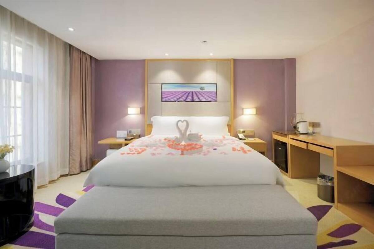 Ein Hotelzimmer mit Bett, Nachttischen, einem Schreibtisch und einem Bild an der Wand.