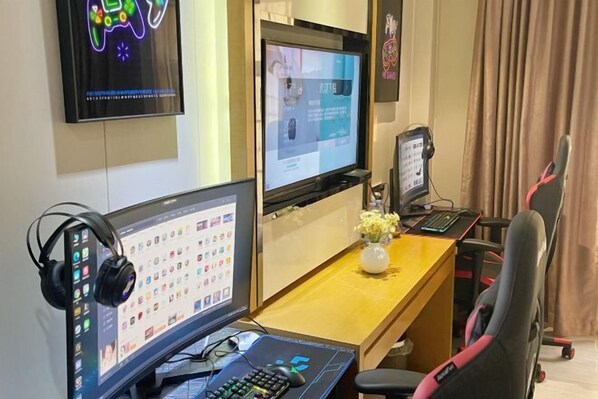 A modern office setup with multiple monitors, a gaming chair, and a desk with a vase of flowers. - Lavande Hotel (Zhuhai Gongbei Port Plaza Light Rail Terminal Store) (Zhuhai)