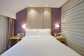 A hotel room with a large bed, two bedside tables with lamps, a wooden nightstand, and a window with blinds. - Lavande Hotel (Zhuhai Gongbei Port Plaza Light Rail Terminal Store) (Zhuhai)