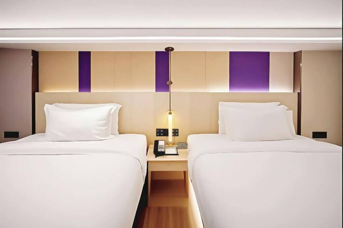 Ein Hotelzimmer mit zwei Betten, einem Nachttisch mit Lampe und einem modernen Kopfteil.