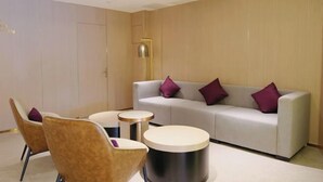 A modern hotel room with a white sofa, two round side tables, and two brown chairs. - Lavande Hotel (Zhuhai Gongbei Port Plaza Light Rail Terminal Store) (Zhuhai)