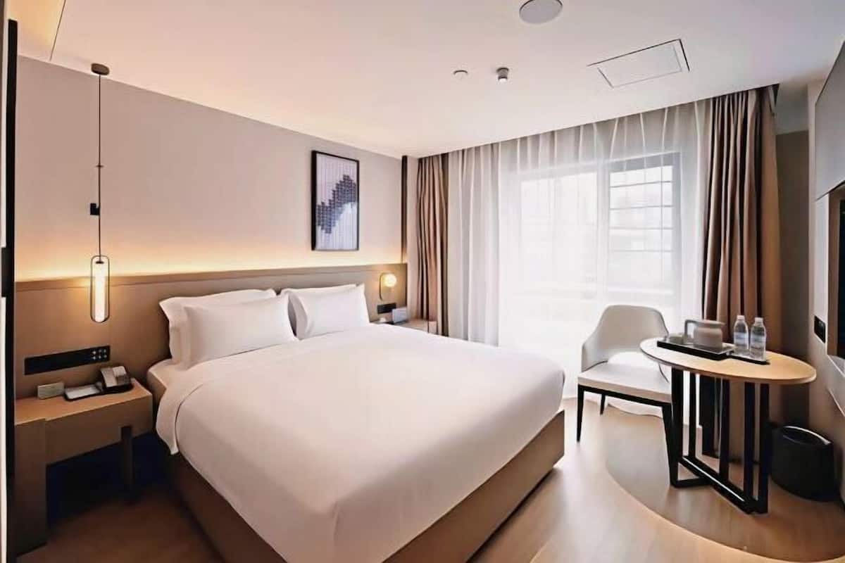 Ein Hotelzimmer mit einem großen Bett, Nachttischen, einem Schreibtisch und einem Sessel.