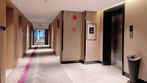 A hotel hallway with a carpeted floor, wooden walls, and an elevator. - Lavande Hotel (Zhuhai Gongbei Port Plaza Light Rail Terminal Store) (Zhuhai)