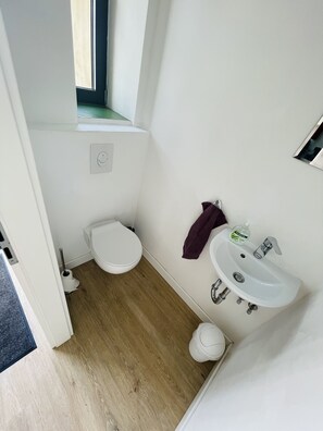Un baño pequeño y funcional con inodoro, lavamanos y una ventana sobre el inodoro.